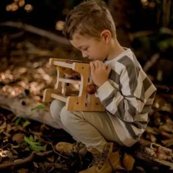 boy looking through wooden microscope toy