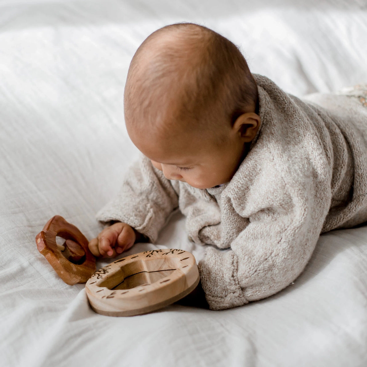 Baby playing with natural wooden shell rattle and mirror