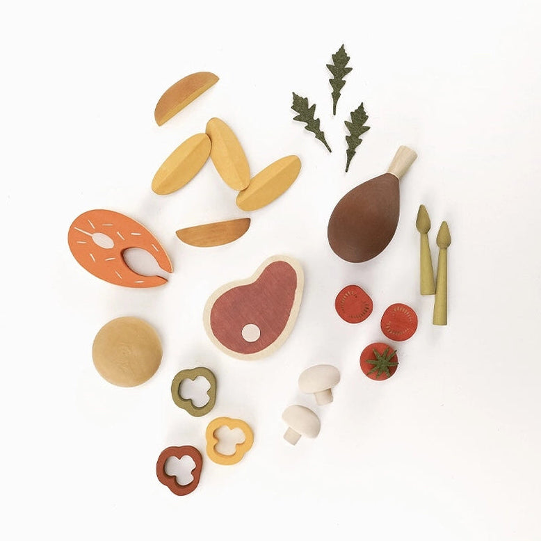 Sabo Concept wooden play food dinner set including a salmon slice, bread, chicken leg, potato wedges, asparagus, mushrooms, tomatoes, and peppers.