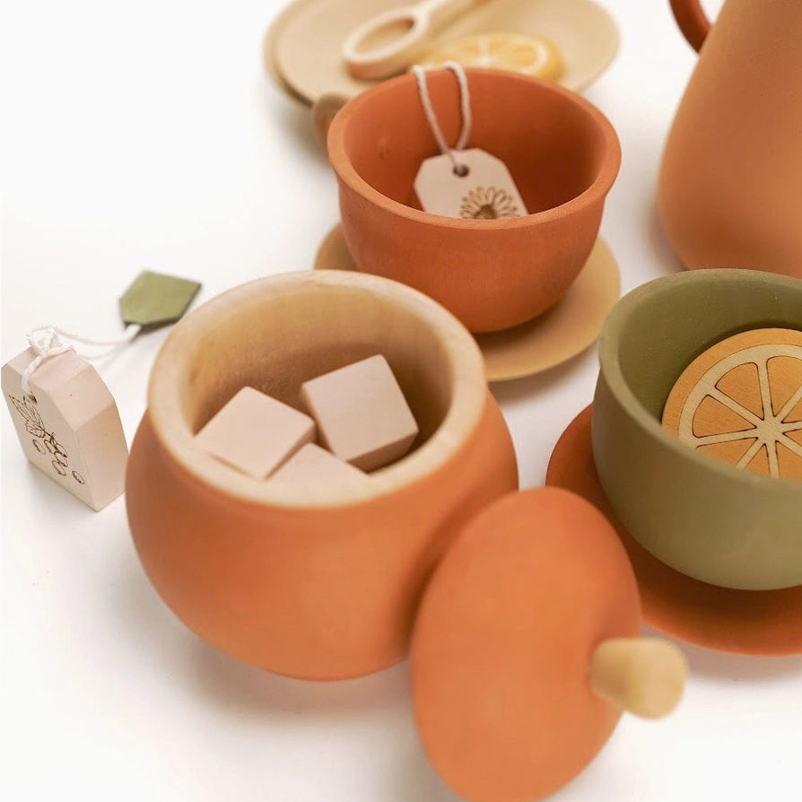 Set of terracotta colored wooden toy teapot and cups with tea accessories 