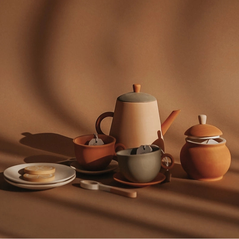 SABO concept terracotta-colored wooden toy tea set including a teapot, cup, saucer, lidded sugar bowl, and a plate with lemon slices/