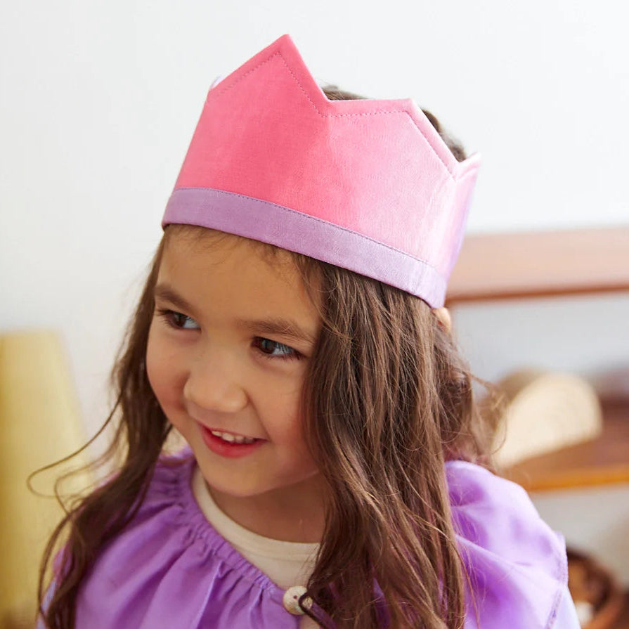 A girl with long brown hair wearing Sarah's Silks pink and purple Blossom crown and cape. 