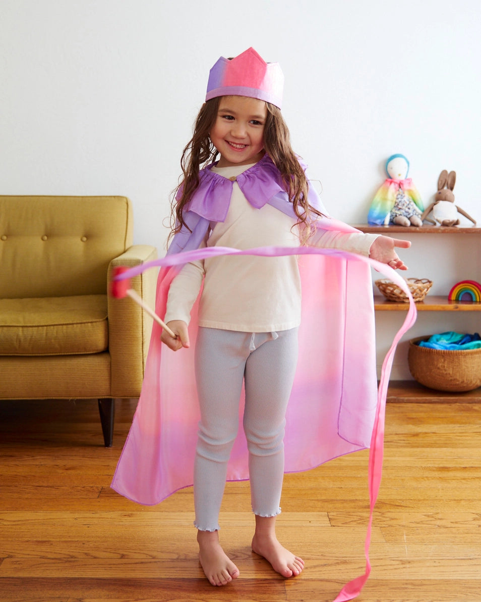 A little girl wearing Sarah's Silks blossom crown, pink and purple cape, and holding a matching heart streamer wand.