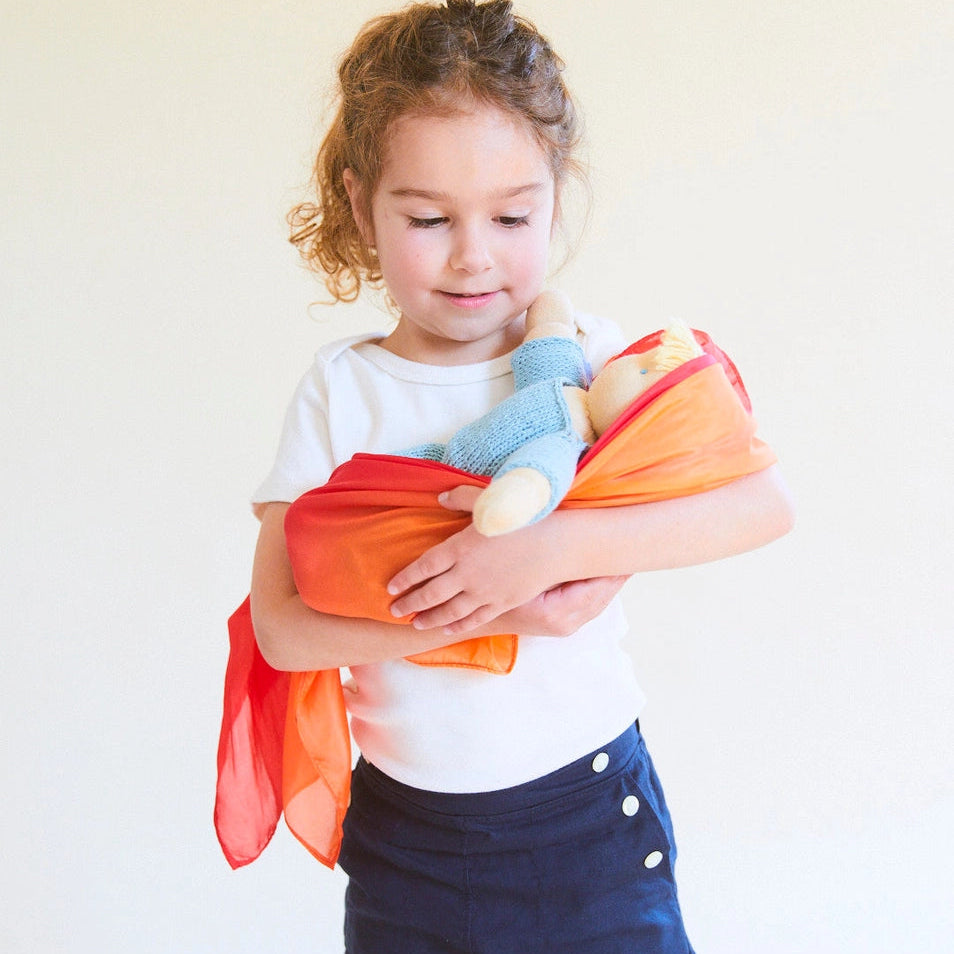 Child holding a doll wrapped in a enchanted fire playsilk