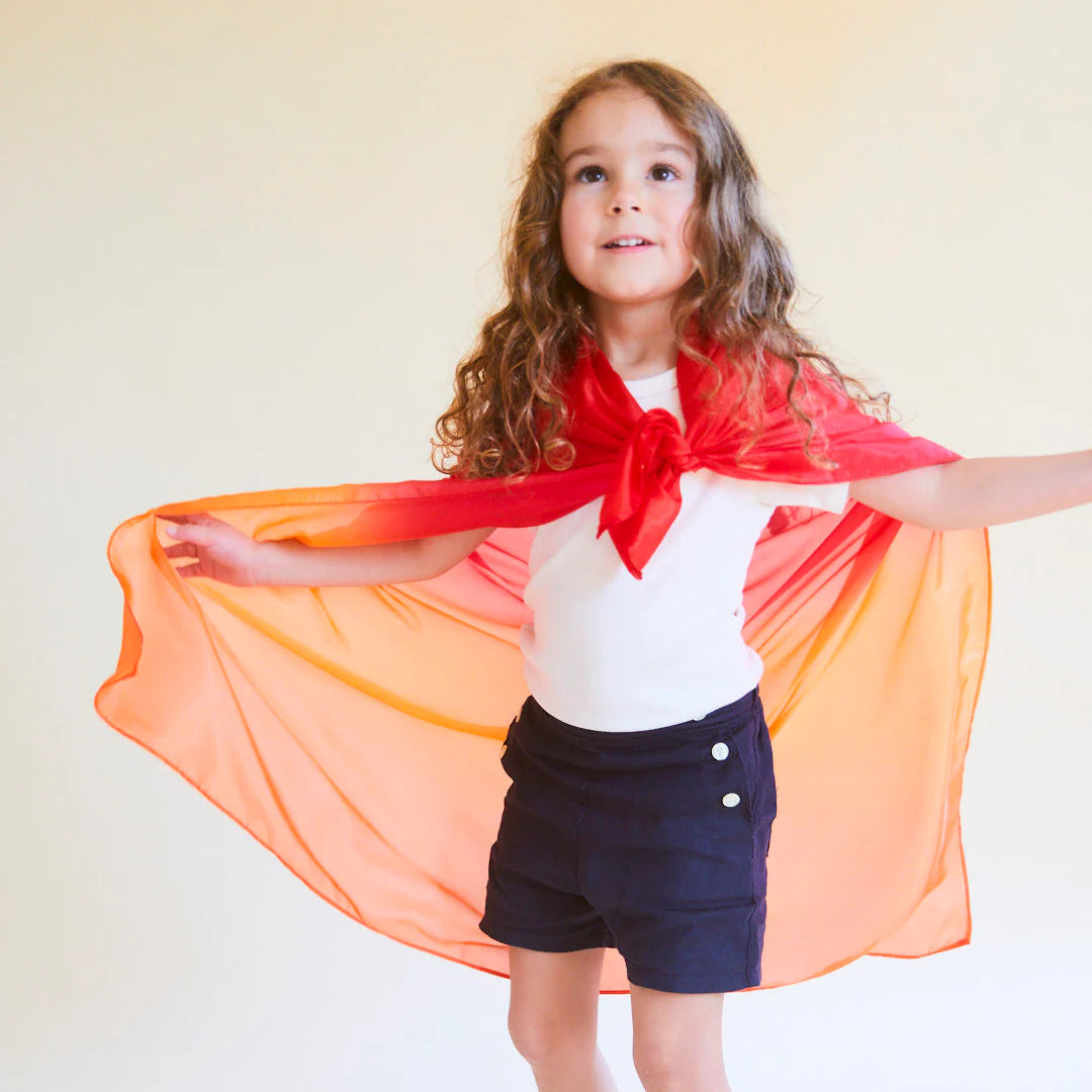 Child wearing a red and orange enchanted fire playsilk as a superhero cape 