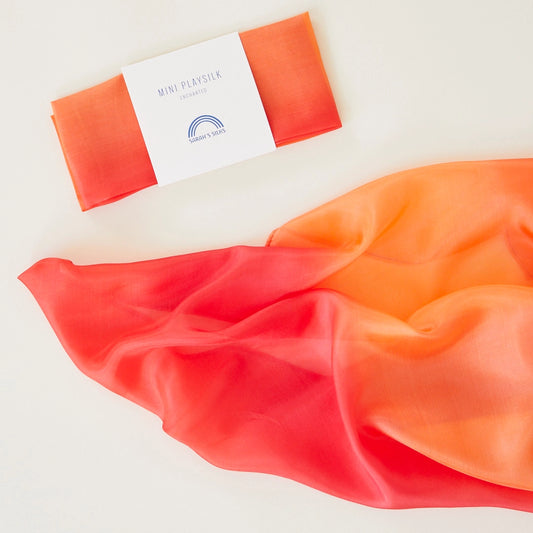 Sarah's Silks mini enchanted fire playsilk blends red and orange fabric with a folded package labeled 