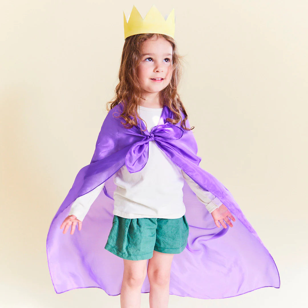 A girl wearing a Sarah's Silks solid purple playsilk as a cape. 
