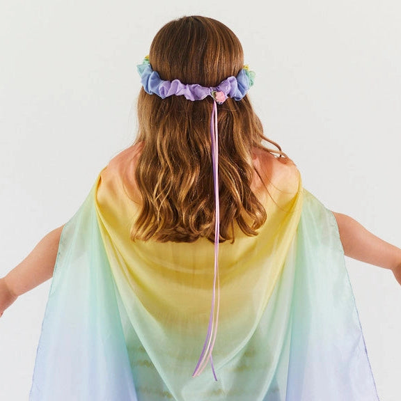 Child wearing a colorful rainbow cape and headband garland 