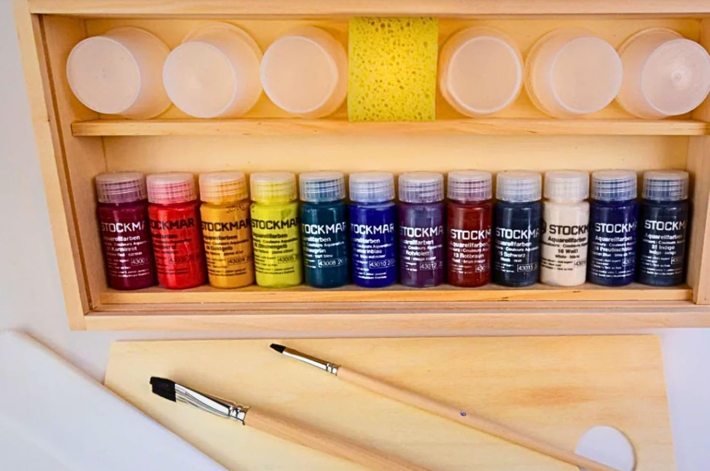 Set of Stockmar watercolor paint bottles with brushs, sponge, paint containers, palette in a wooden box.