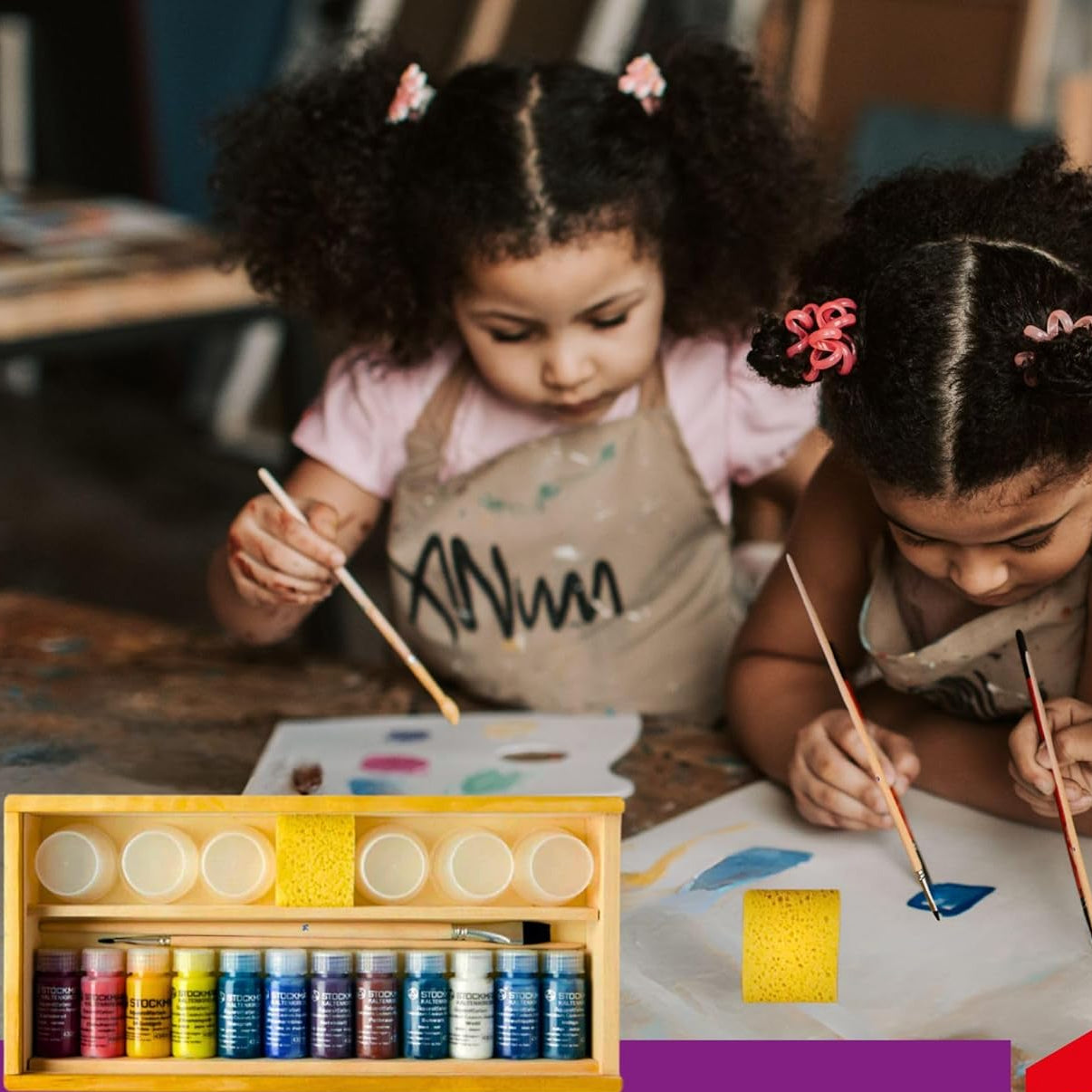 Two children painting with a set of stockmar paints, surrounded by art supplies.