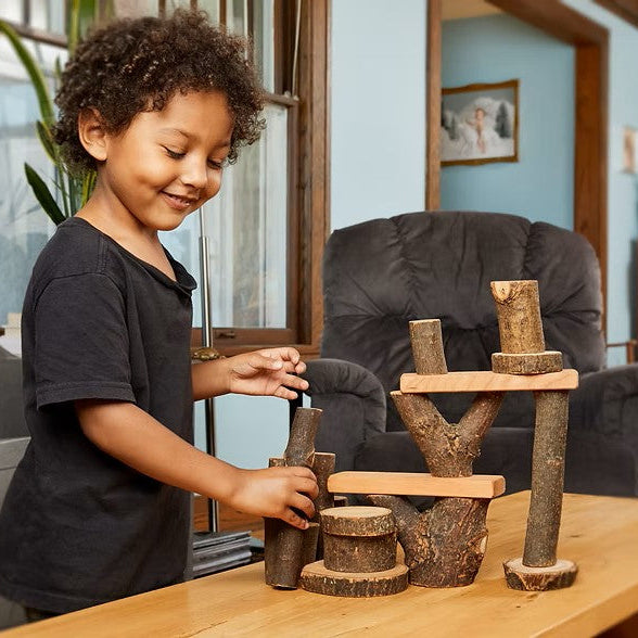 A young child building with rustic giant wooden tree blocks 