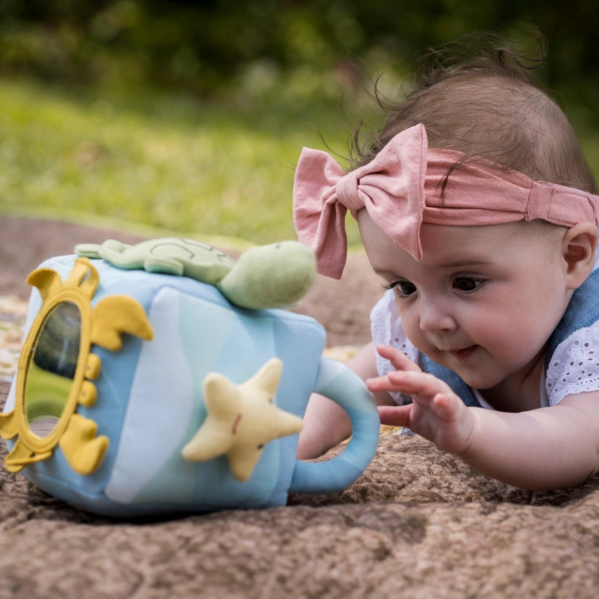 Baby playing with organic ocean activity cube toy with a crab mirror, turtle, star fish, rattle and squeaker