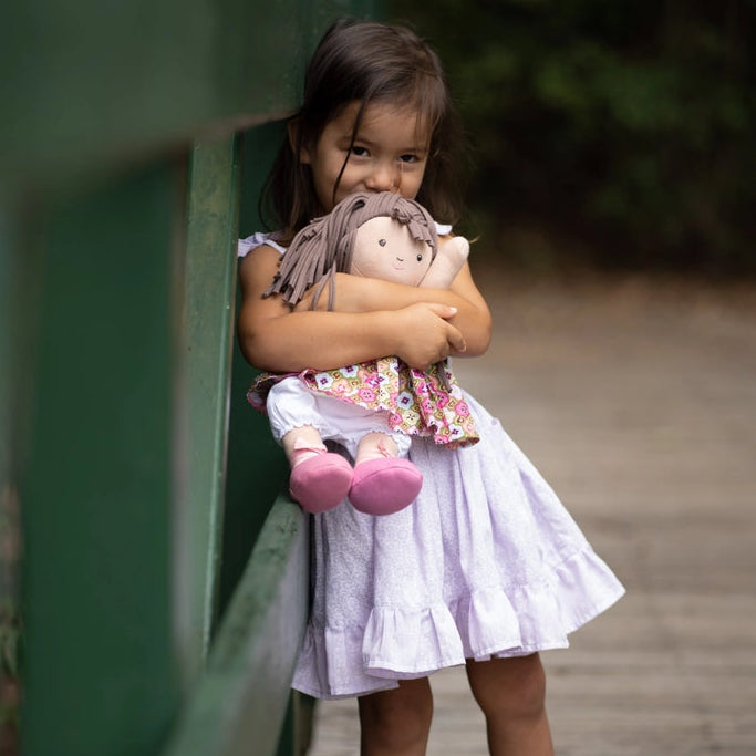 Young girl holding a soft doll with jointed arms and legs 