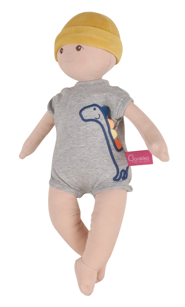 Organic baby boy doll wearing a gray outfit with a dinosaur design and a yellow hat 