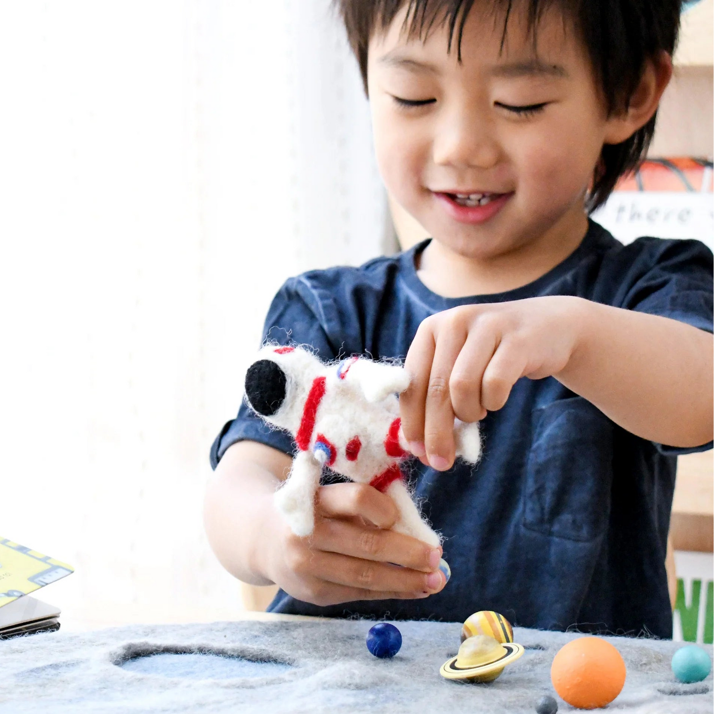 boy playing with Tara Treasures needle-felted astronaut doll