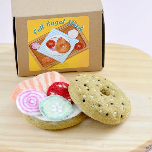 Felt play food bagel sandwich meal on a wooden cutting board with a cardboard box labeled Felt Bagel Shack'.