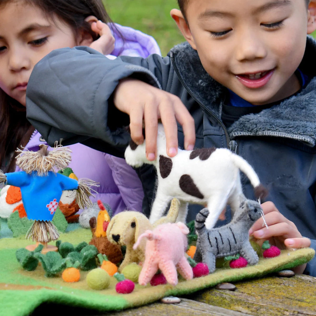 Boy and girl playing with Tara Treasures felt barnyard animals cow, cat, pig, dog and chicken on a farm playmat
