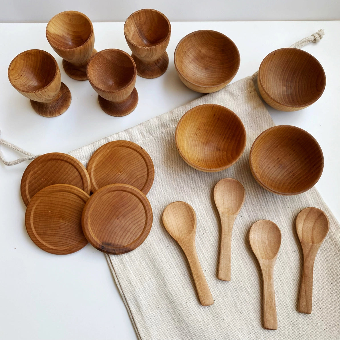 Wooden  toy dish set including plates, bowls and spoons with natural finish.