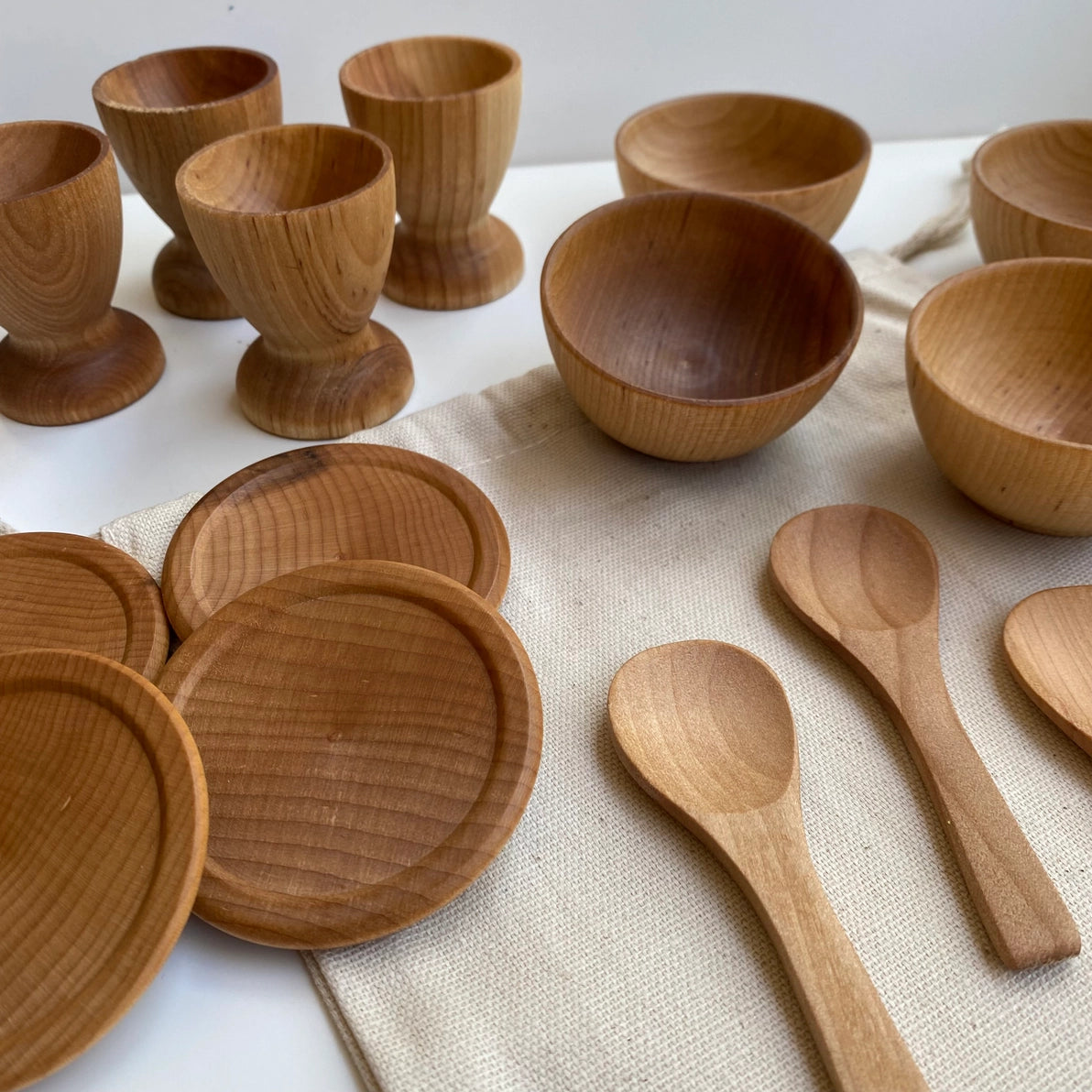 Montessori wooden  dish set toys including plates, bowls and spoons with natural finish.