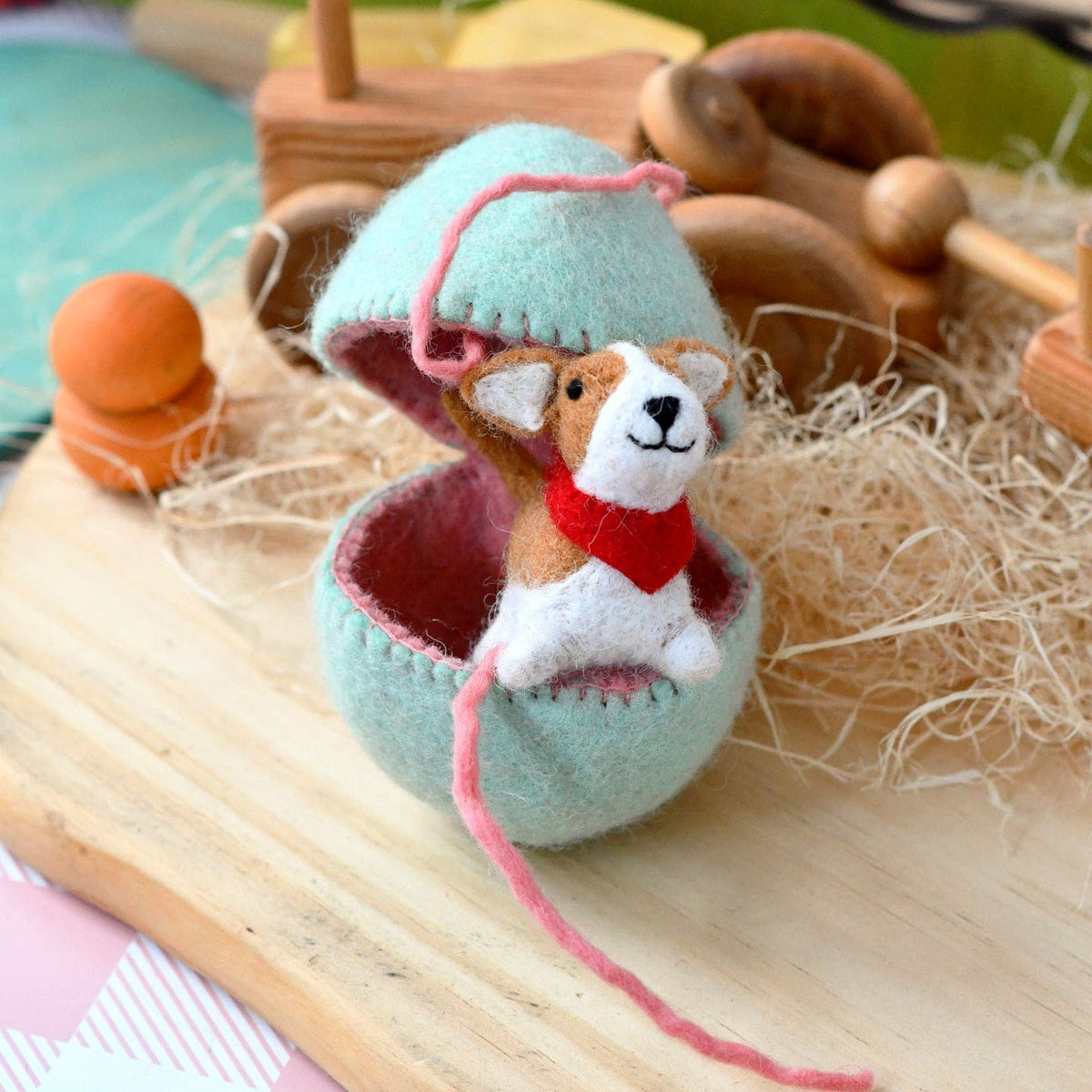 Toy brown Corgi dog wearing a red bandana inside a felted Easter egg