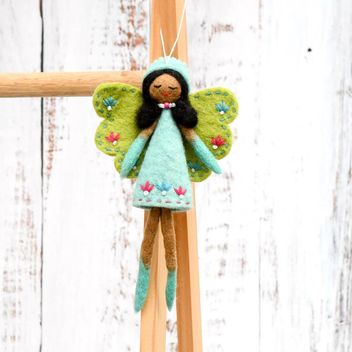 Tara Treasures felt fairy with green wings, brown skin and black hair, wearing a turquoise dress embroidered with flowers