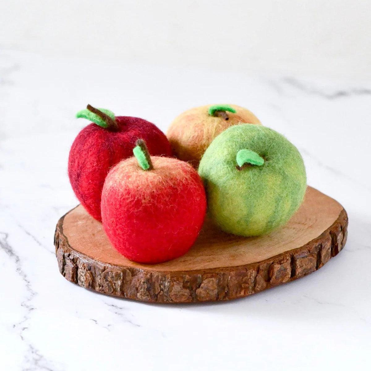 Four felt play food apples on a wooden stand