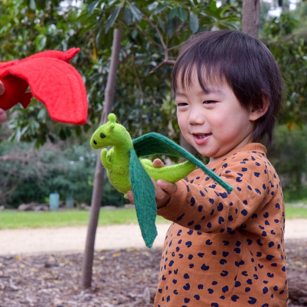 Child playing with a felt green plush dragon toy