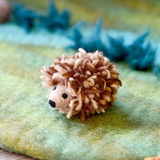 Small hedgehog felt toy on a textured green playmat