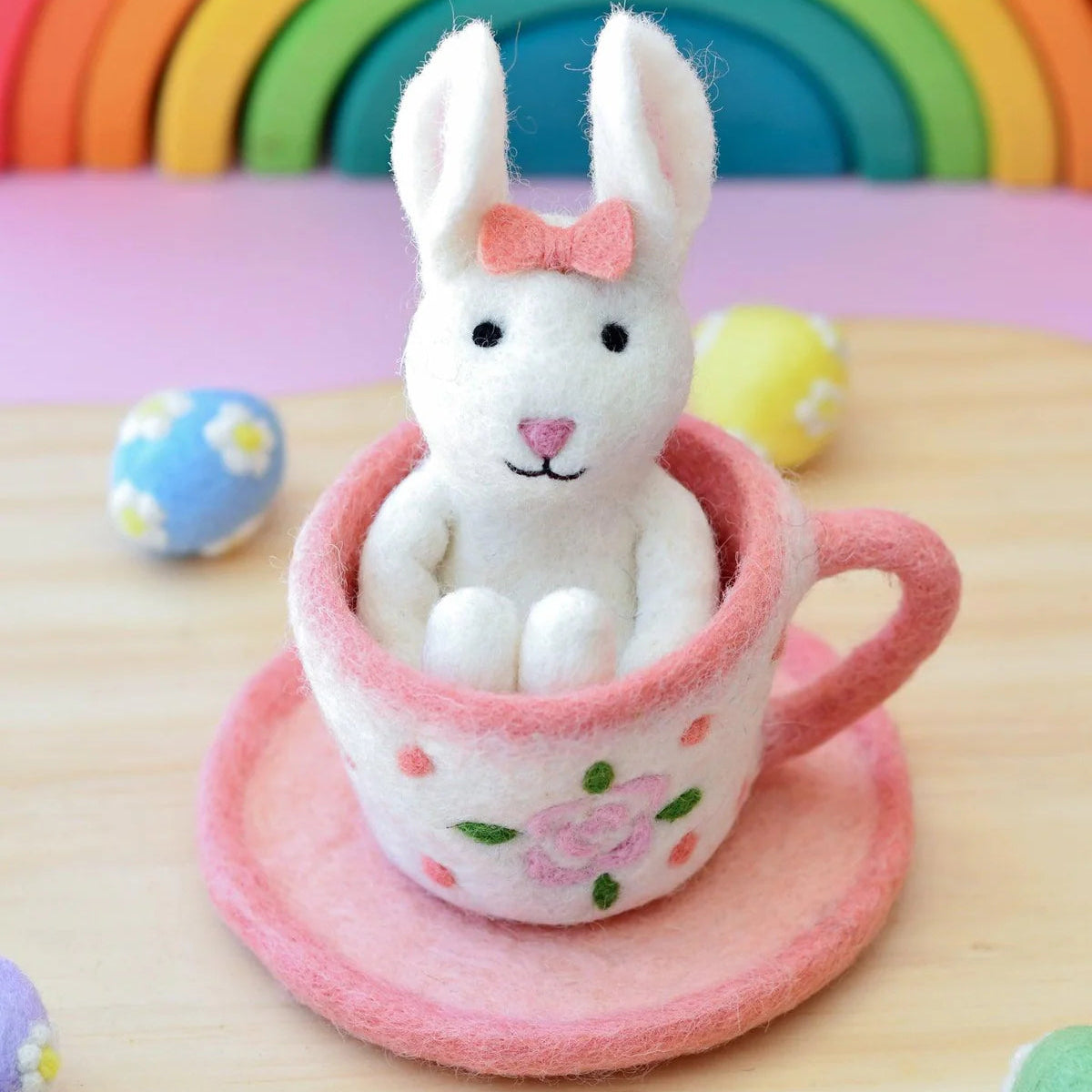 White felt bunny toy with a pink bow in a floral dot teacup with saucer