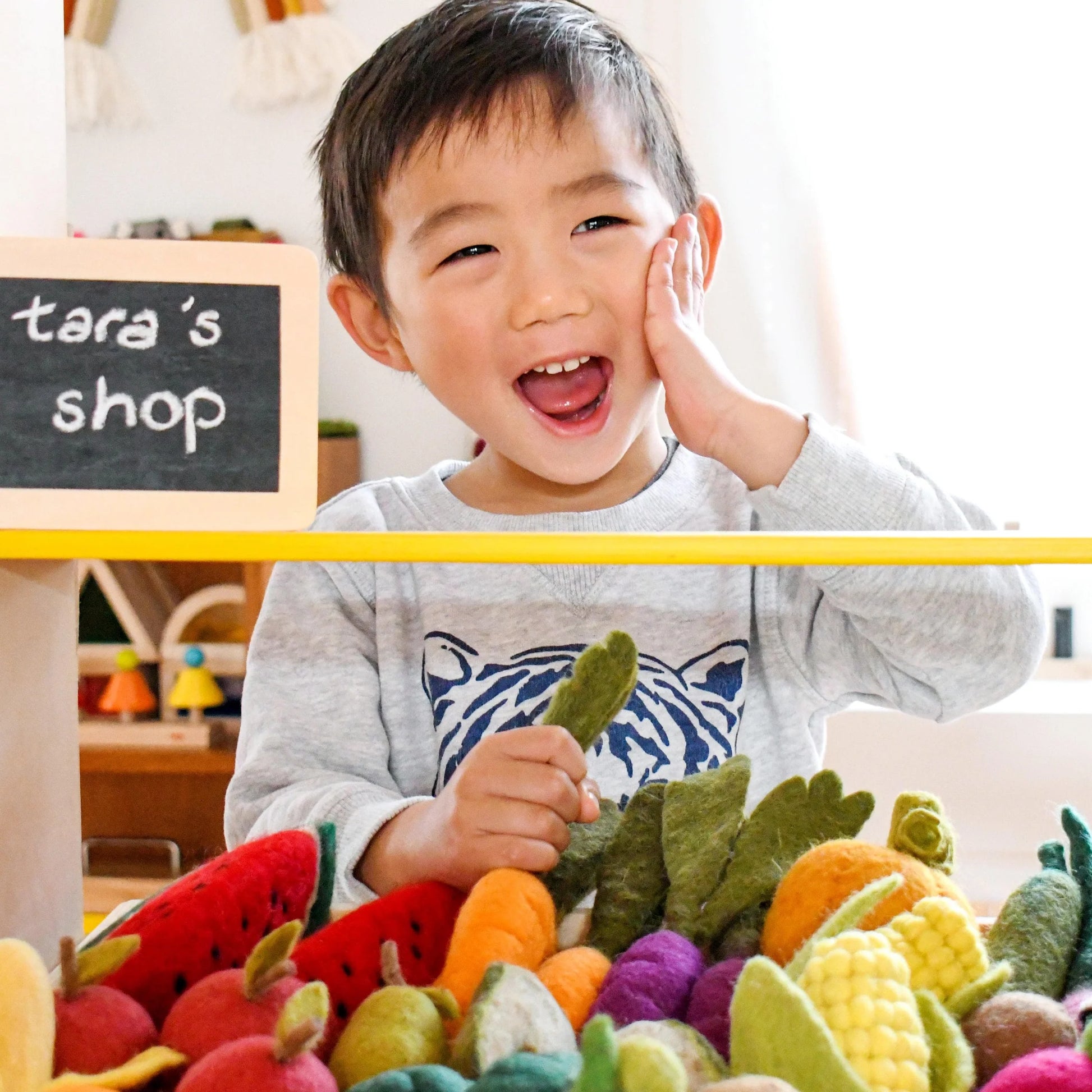 Boy with Tara Treasures needle felted play food fruits and vegetables toys