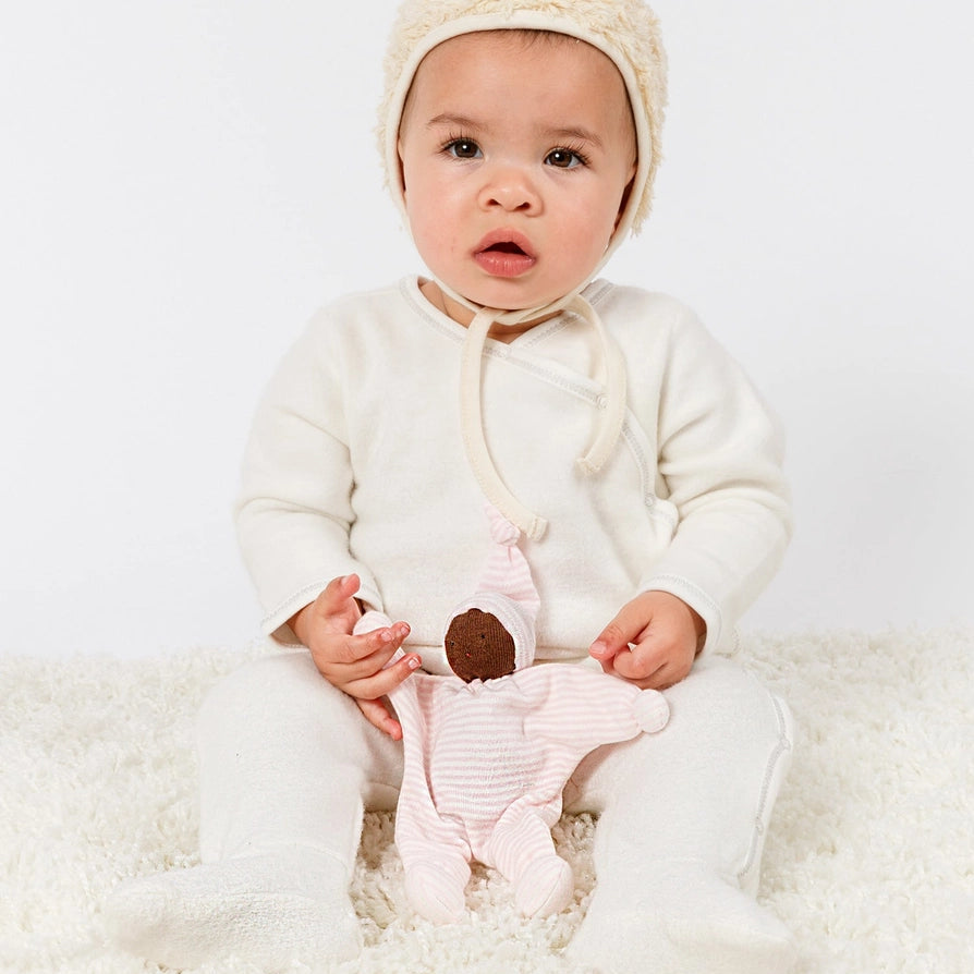 Baby holding Under the  Nile Baby Buddy Doll with brown skin and pink stripes
