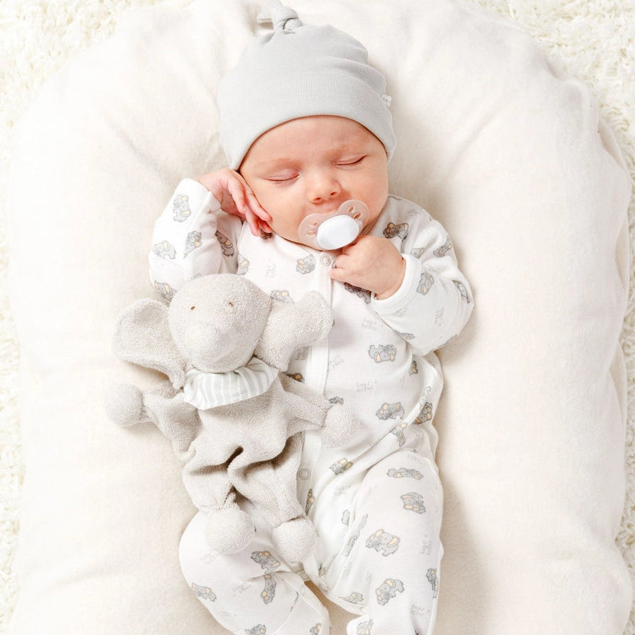 Sleeping newborn baby holding an Under the Nile organic elephant lovey toy.