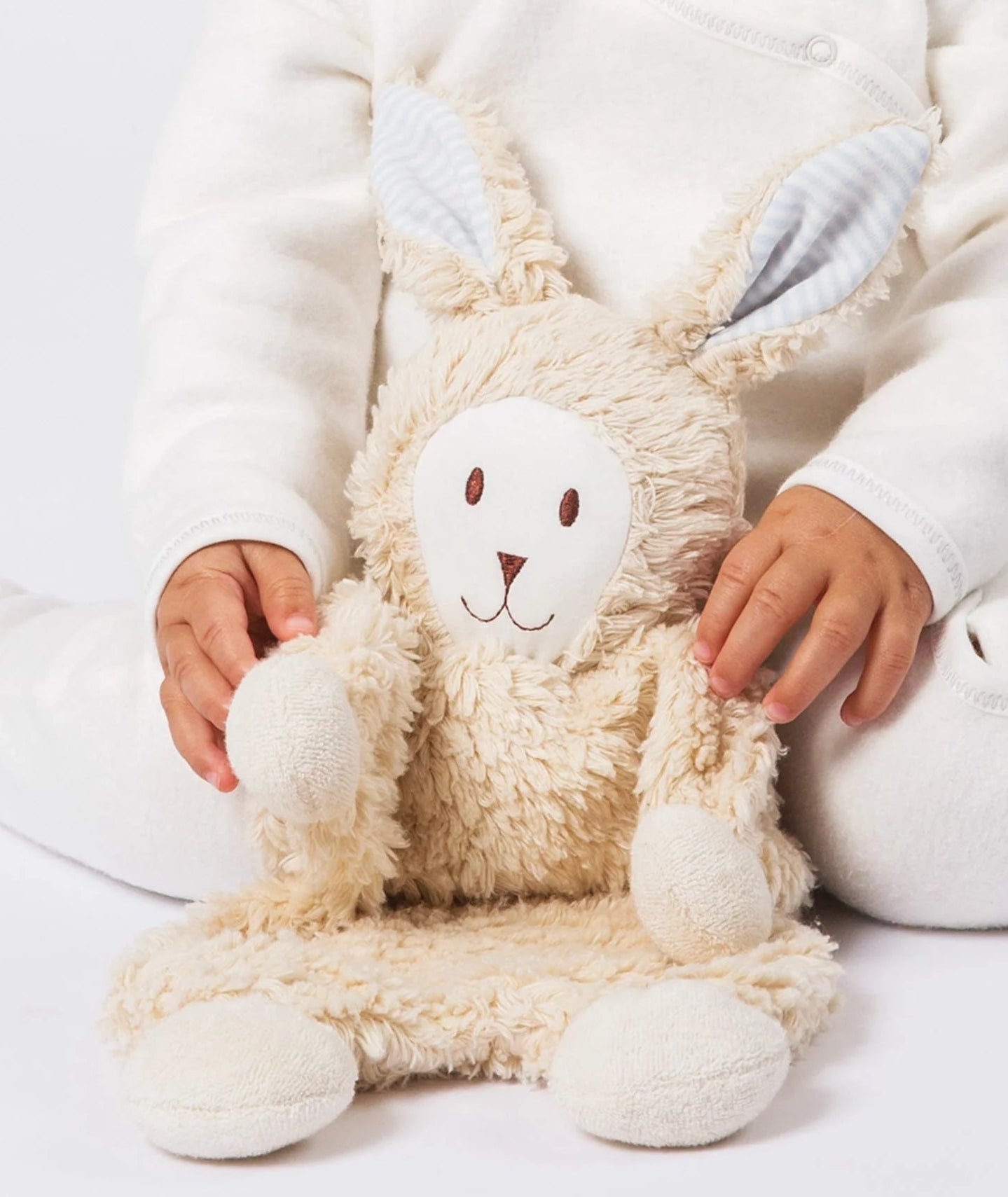 baby holding Under the Nile Sherpa Snuggle Bunny stuffed animal with blue ears