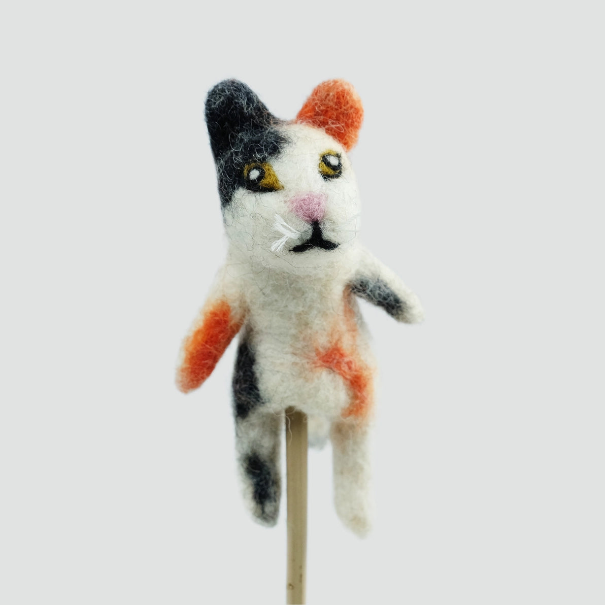 A hand felted calico cat finger puppet