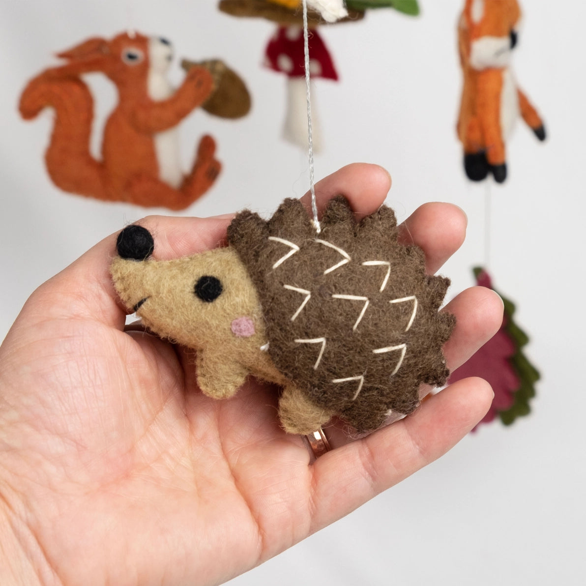 Hand holding a small felt hedgehog 