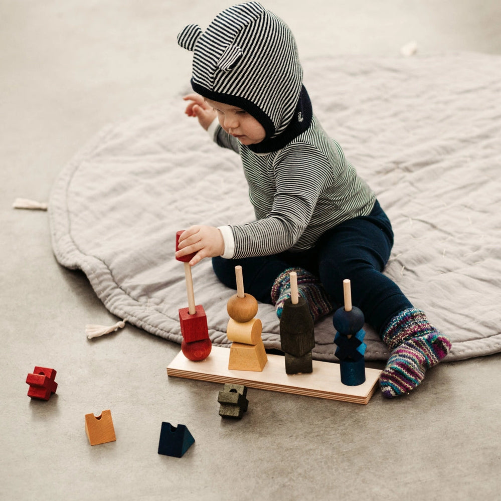Child playing with wooden rainbow stacking and sorting shapes.