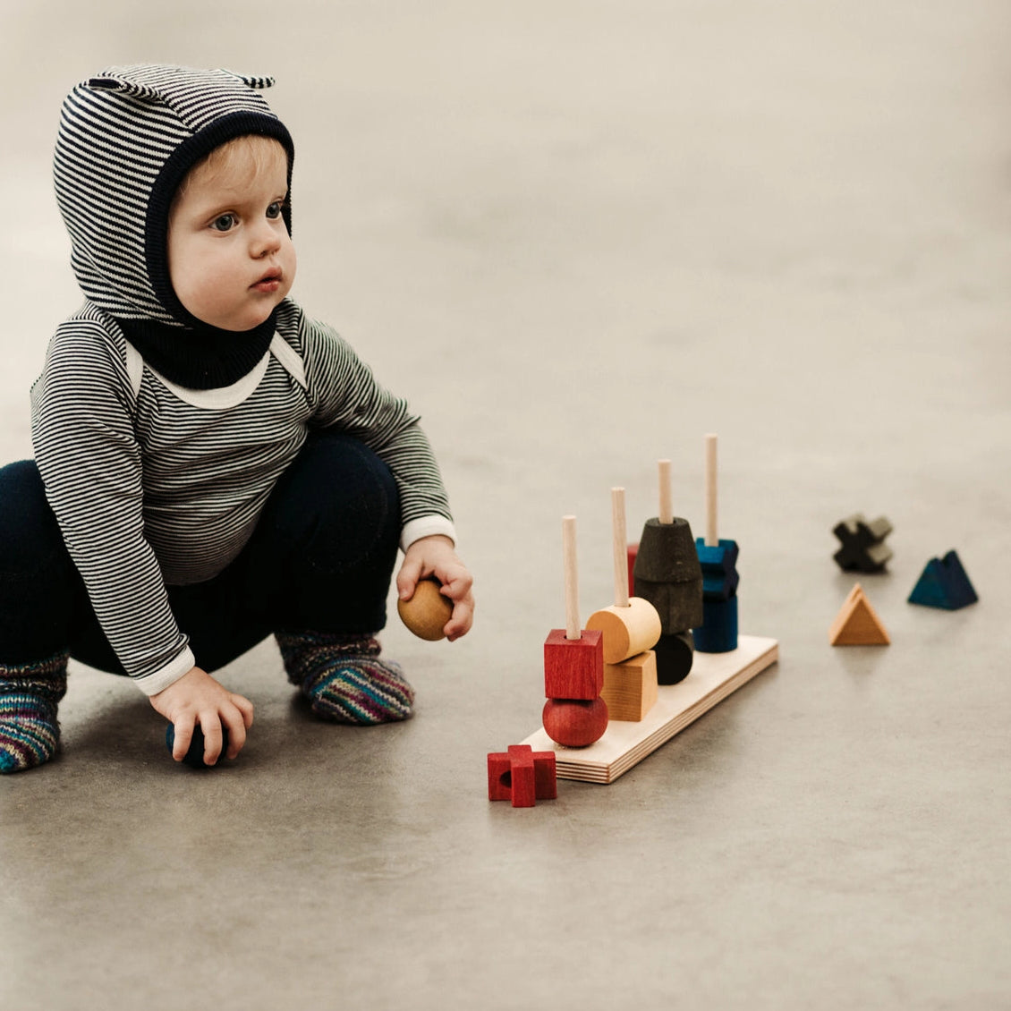 Toddler child playing with wooden rainbow stacking and sorting shapes.
