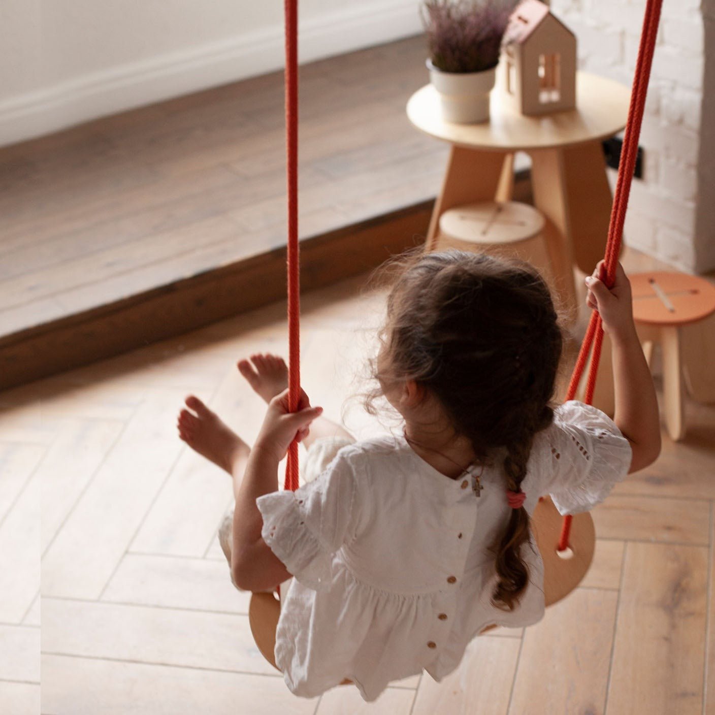 girl on wooden swing with orange rope